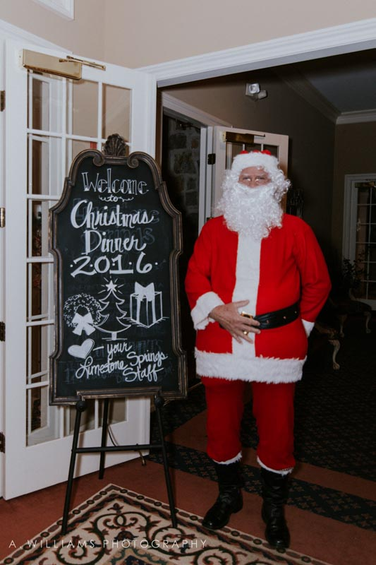Santa posing by Christmas dinner sign